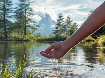 hand scooping water from lake